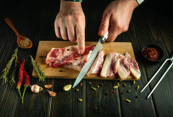 Slicing pork belly to prepare a fatty and rich dish in a restaurant kitchen. Knife in the hand of a...