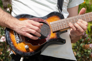Guitarist playing an electric guitar outdoors close up
