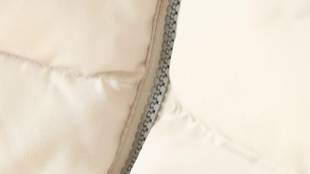 White puffy winter jacket and zipper as a background close-up, white 
