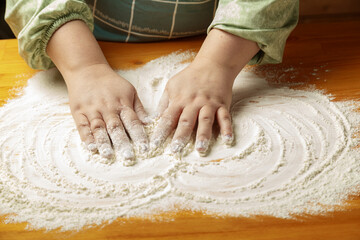 Women's hands spread a thin layer of flour on the table - obrazy, fototapety, plakaty