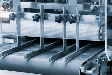 A conveyor belt with a machine on it. The machine is made of metal and has a black and silver color