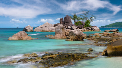 A rocky shoreline with a small island in the middle of the ocean. The water is calm and blue