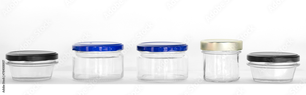 Poster a row of clear jars with blue lids. the jars are of different sizes and are lined up on a white surf