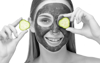 Beautiful smiling woman with clear skin holds a cucumber near her face. She applied the mask to her face. Cosmetological skin care