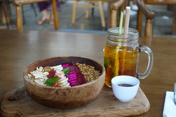 Acai bowl topped with various fruits and iced tea