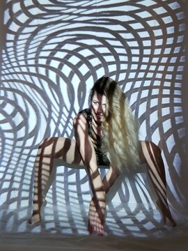 Fototapeta Young woman in stylish black bodysuit and elegant high heels standing in front of geometric pattern projection, creating optical illusion of merging seamlessly with the futuristic background