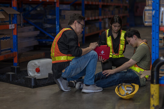 First aid support accident at work of worker at factory. Male worker has an accident on the floor in warehouse site.