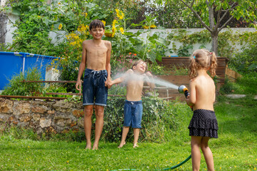 Siblings have a blast with water hose on sunny day in garden - 784035687