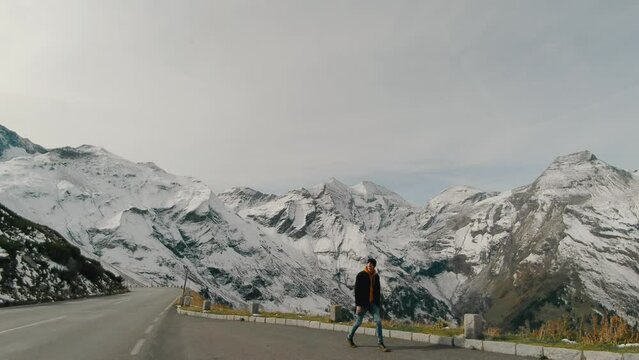 Tourist man walking on a road in the snowy mountains, Grossglockner, Austria
