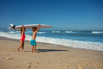 Young surfers ready to catch waves hold surfboard on shoulders - 784044297