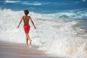 Youthful beachgoer in vibrant swimwear dashes along the seafront - 784045818