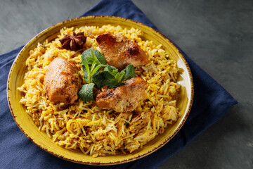 Indian Chicken Biryani with Spices on Yellow Plate, Trendy Indian and Pakistani Dish, Close-up