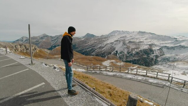 Tourist man walking on a road in the snowy mountains, Grossglockner, Austria