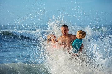 Man and kids splash joyfully in sea with waves crashing around