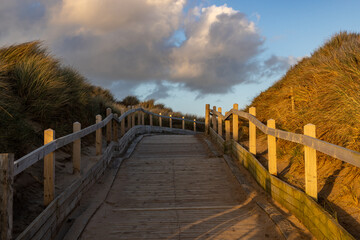 A wooden boardwalk at the coast, with evening light