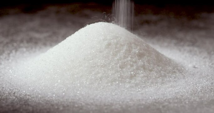 Pouring White Granulated Sugar into a Pile on a Grey Background