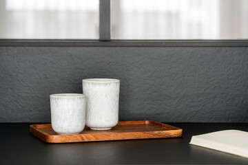Ceramic cups with different size on bamboo board on countertop in kitchen