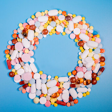 Frame with colorful pills and capsules on a blue background. Place for text