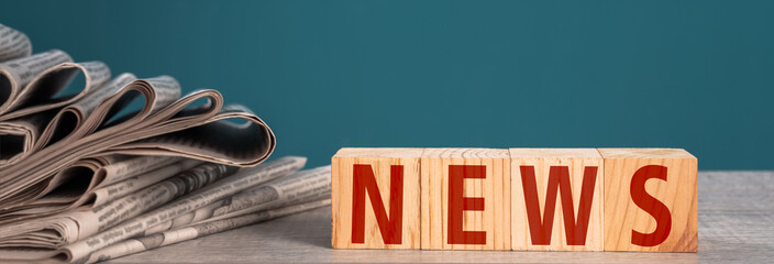 Newspapers and wooden cubes with the word "news" on a blue background stock photo