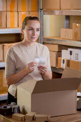 Woman checking goods in a box. Postal service and small business concept