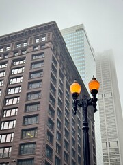 low angle view of the top of the Chicago skyscraper with an urban street lamp lit under a foggy sky...