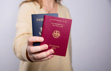 Close up of a woman in yellow sweater holding a German and an American passport