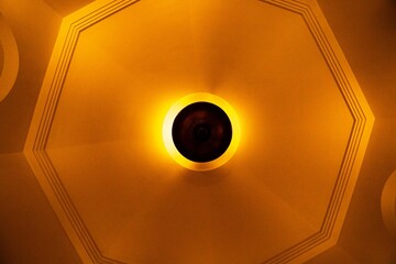 Lustre em teto alto com luz amarela. 