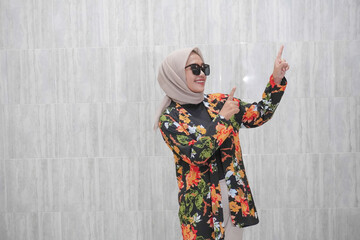 Fototapeta na wymiar The smiling expression of an Indonesian woman wearing a hijab wearing a beautiful floral patterned dress