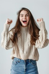 Excited female in a sweater with fists pumped, expressing success on a white background - obrazy, fototapety, plakaty
