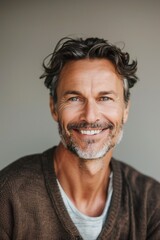 Obraz premium Middle-aged man with a charming smile in a neutral background portrait