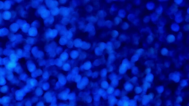 Abstract shiny glitter 4k video background. Blue glitter blurred background with sparkling texture. Dark sapphire shimmering light, sequins sparks and glittering glow foil background.