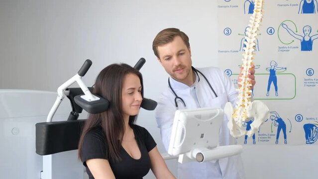 Doctor holding a spine model, woman sitting on machine for an event