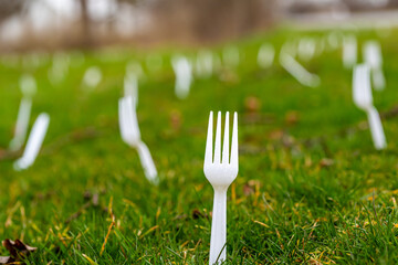 Many white plastic forks planted in lawn, forking, grass, as April Fool joke.