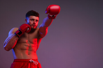 Man in boxing gloves fighting on color background, low angle view. Space for text