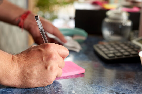 This image vividly captures the essence of productivity with a close-up of a hand writing on a pink sticky note