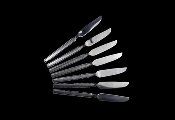 Food knives mounted on top of each other in an artistic and elegant way in black and white.