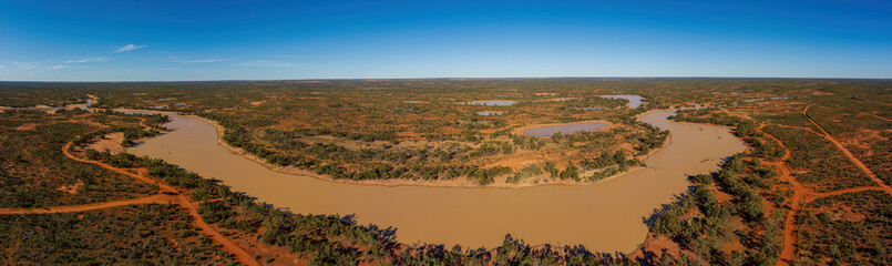 A waterhole at a large cattle station in the Australian outback provides a vital oasis for livestock and wildlife, sustaining life in the arid landscape.