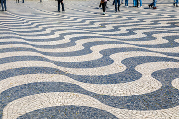 People Walking on Undulating, Dizzying Waves of Black and White Limestone Tiles on a Sidewalk in Lisbon, Portugal - 784156064