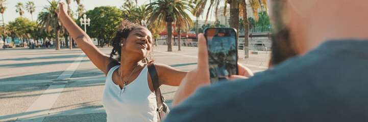 Smiling interracial couple. Man takes picture and video of woman on the phone, Panorama