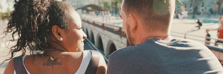 Close-up of an interracial couple standing on bridge. Back view, Panorama