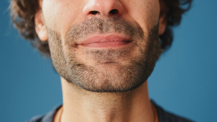Detailed close-up shot of man's mouth in studio on blue background