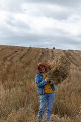 Naklejka na ściany i meble A smiling Latina woman lifting a bale of hay on a hill in the Andes mountains