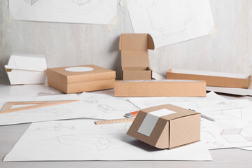 Creating packaging design. Drawings, boxes and stationery on light wooden table, closeup