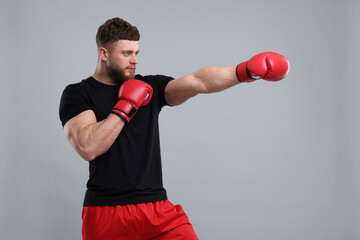 Man in boxing gloves fighting on grey background