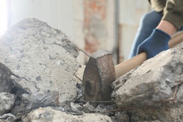 Man breaking stones with sledgehammer outdoors, closeup