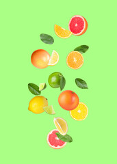 Many different fresh citrus fruits in air on light green background