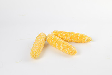 Ears of sweet corn without husks on a table ready to cook or roast isolated on white