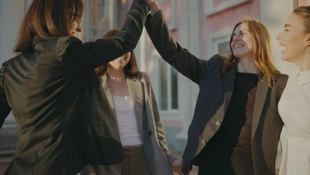 A group of business women rejoice with happiness that their project was accepted. Females high-five each other with joy and hug. Group of satisfied business women.