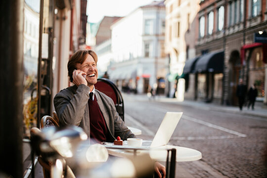 Mature man enjoying a coffee in a cafe while talking on the phone