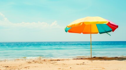 A vibrant beach umbrella stands out against the subtle shades of the sea and sky, a cheerful sentinel of sunny days and gentle breezes.